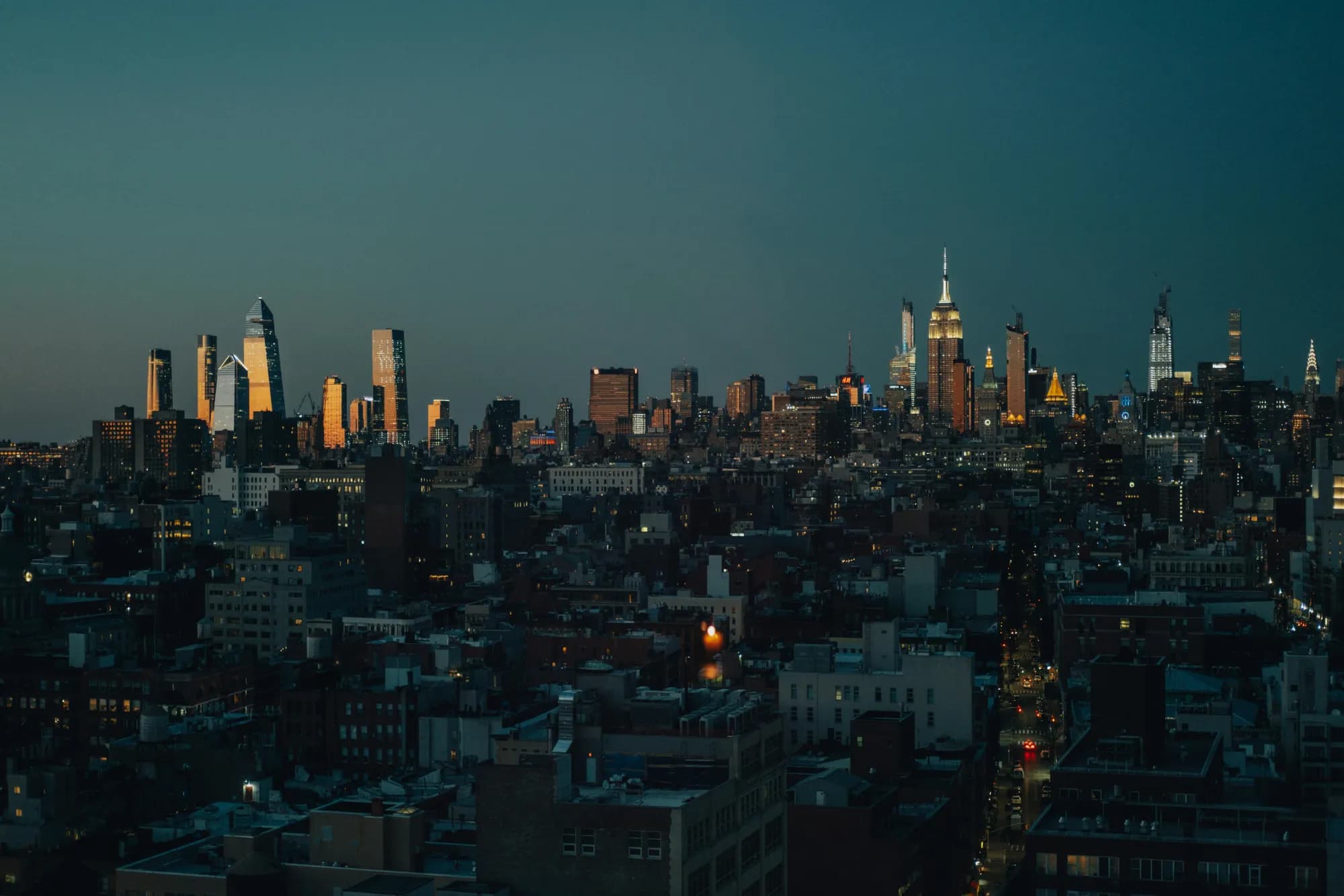 Lower Manhattan skyline at dusk, viewed from the water.